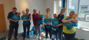Group of people holding first aid manikins