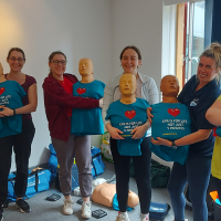 Group of people holding first aid manikins